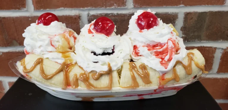 Banana split with strawberry topping, whipped cream and three cherries