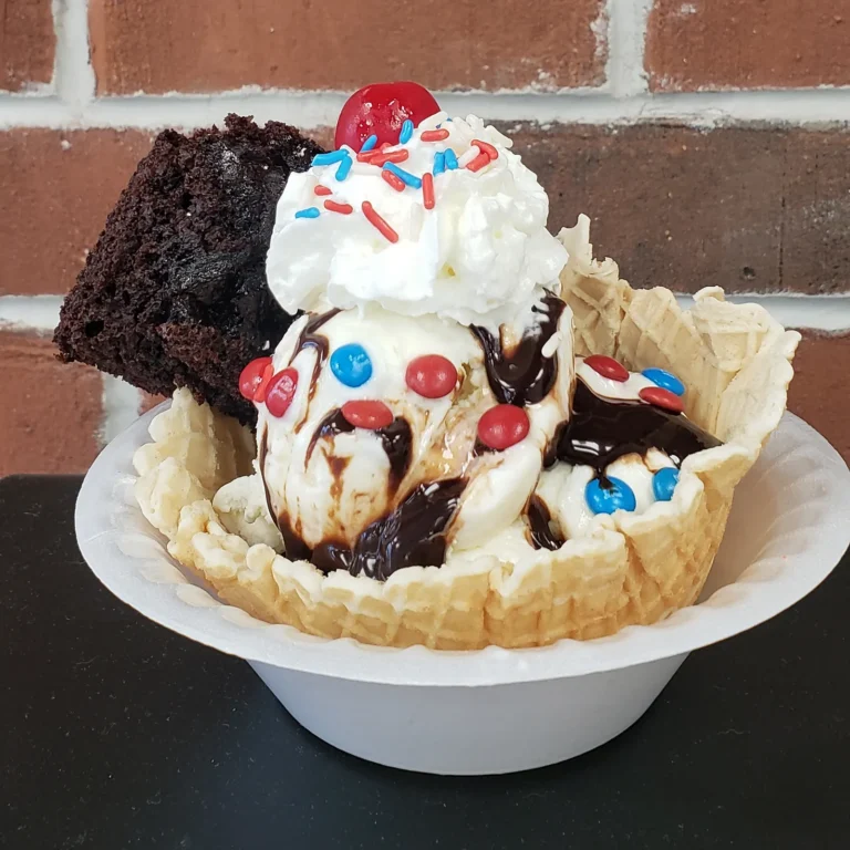 Waffle bowl sundae with a brownie, hot fudge, whipped cream, candies and a cherry