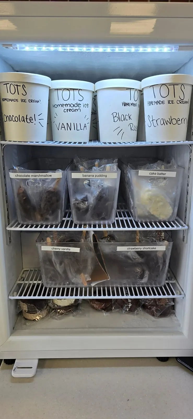 Freezer case stocked with take-home pints and quarts of Tots homemade ice cream