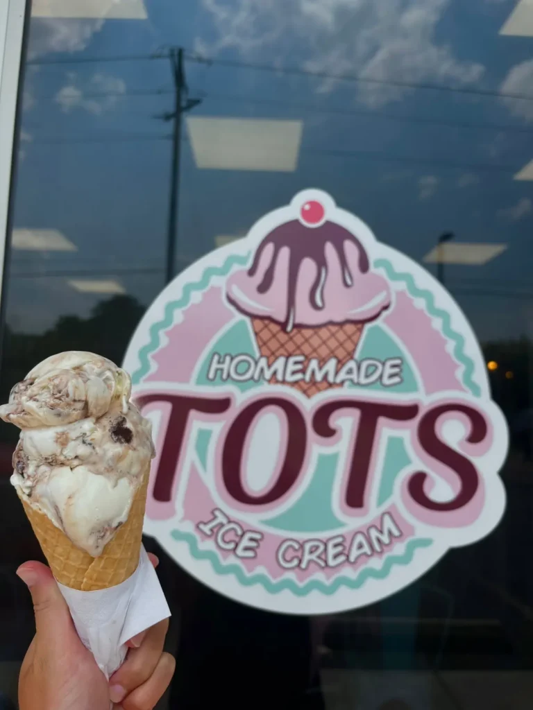 Ice cream cone held up in front of the Tots Ice Cream window logo