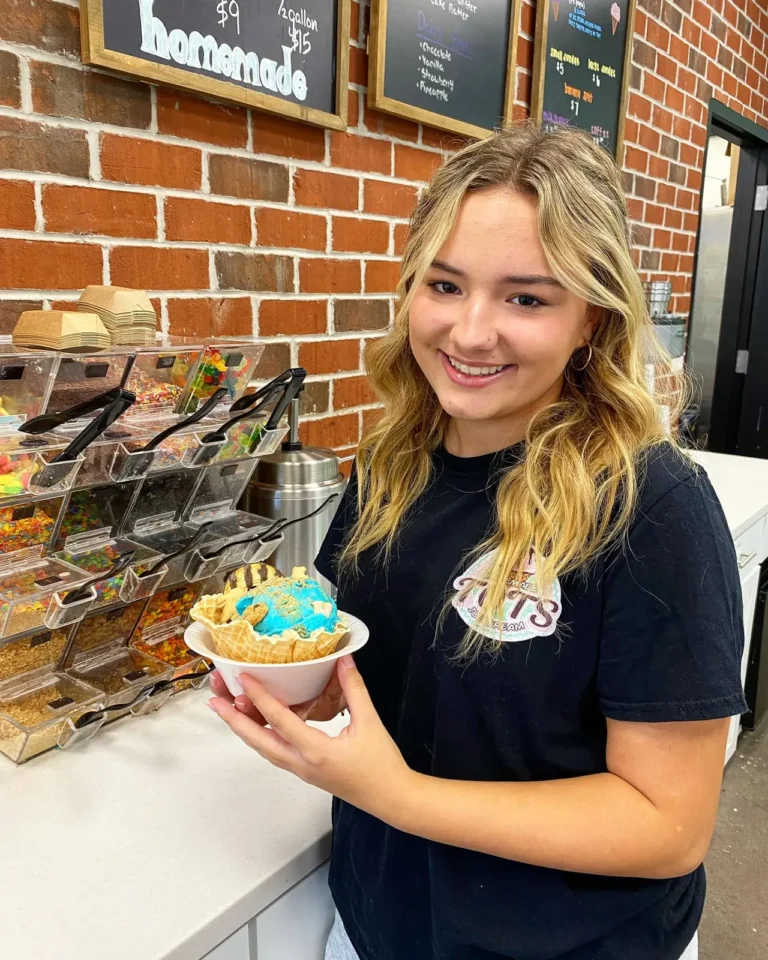 Tots team member holding a waffle bowl sundae by the topping bar