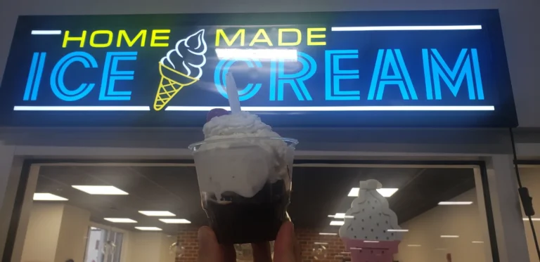 Sundae held up under the lit Home Made Ice Cream sign at Tots