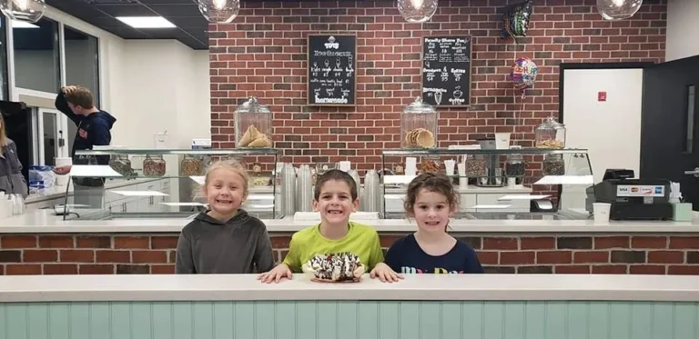 Three young customers smiling at the counter inside Tots Ice Cream in Penn Laird