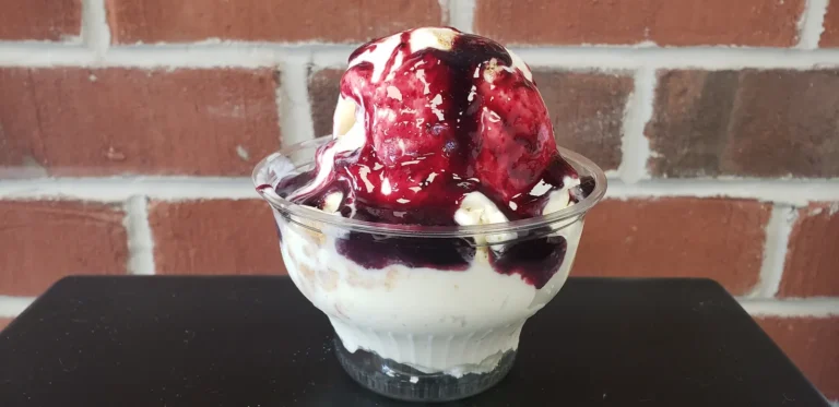 Sundae with black raspberry topping in a clear cup